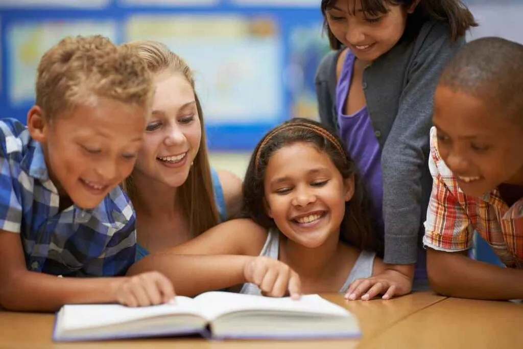 crianças lendo livro, representando qual a melhor idade para aprender inglês